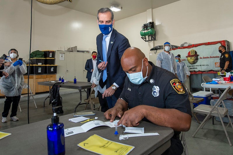 Los Angeles City Fire Captain Leon Dunn takes a rapid antigen test as Mayor Eric Garcetti observes