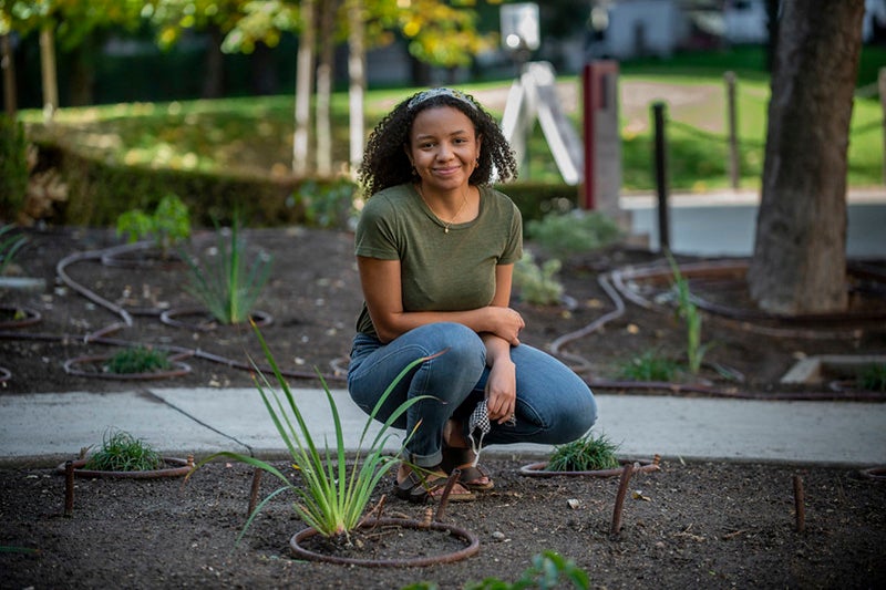 USC student crouches, surrounded by a garden