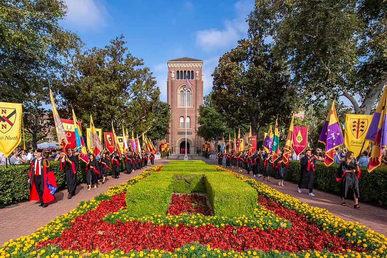 Heraldic flags are marched through between Bovard administration building and Doheny library