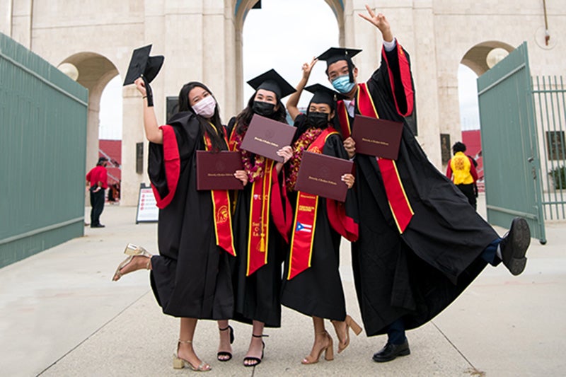 USC graduates jump for a post outside the LA Memorial Coliseum
