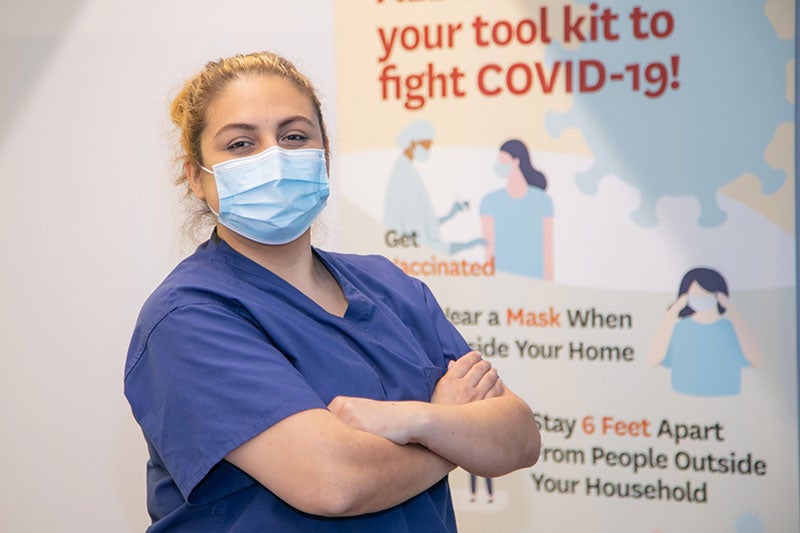 Keck hospital staff wearing a mask in front of a COVID signage