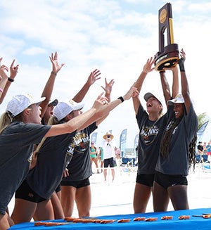 USC women's beach volleyball team holding up their 2021 championship trophy