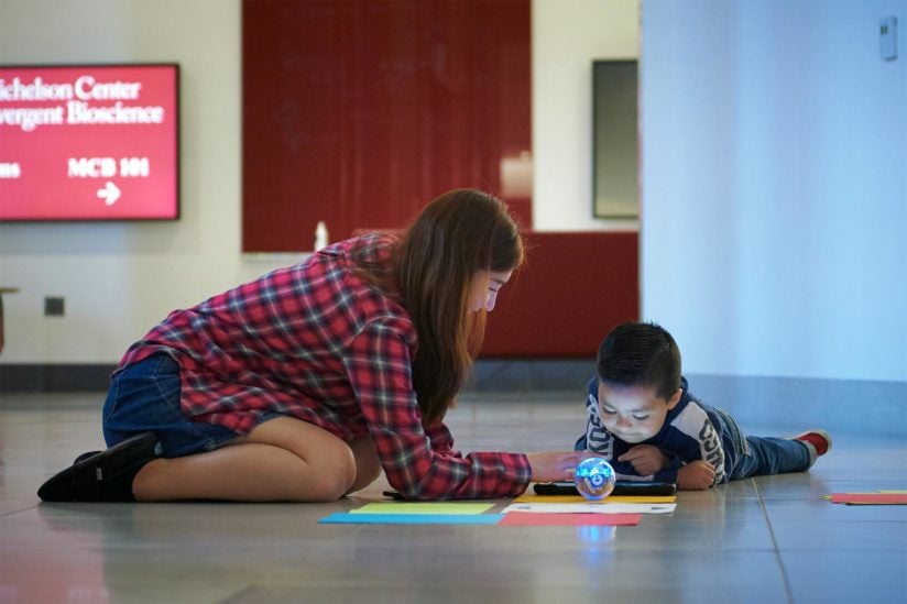 A USC graduate student encourages a student who is programming a robot. 