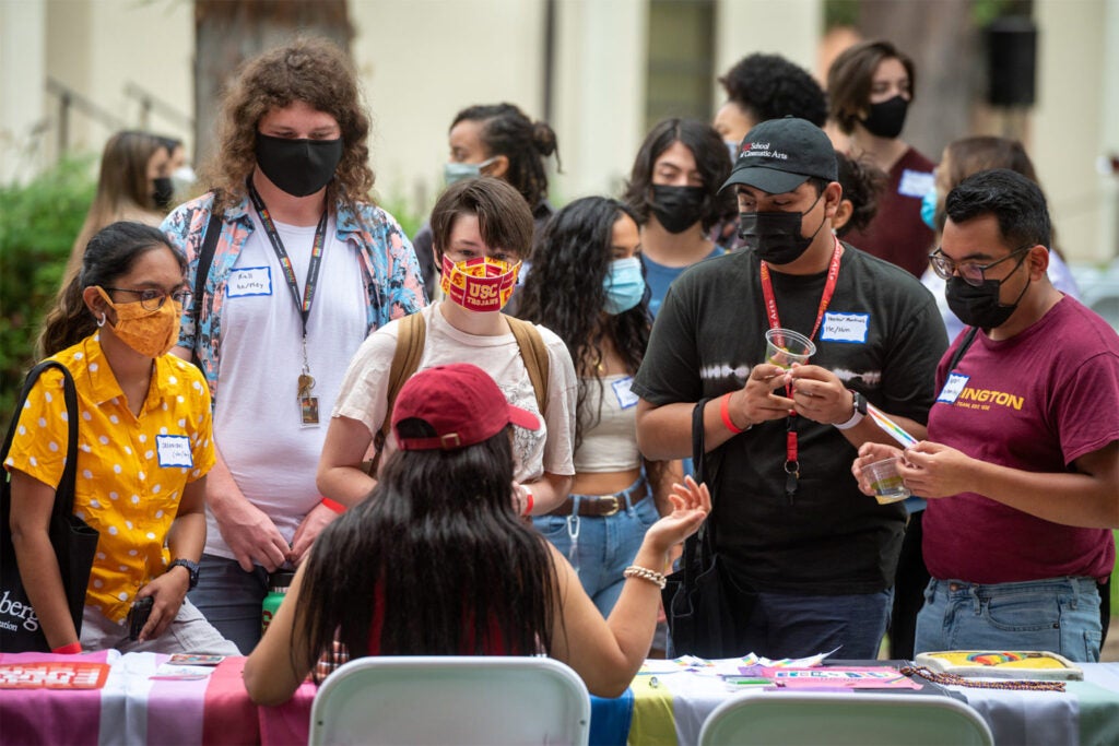 Students talk with Rachel Freeman-Cohen (back to camera) at the LGBTQ+ table.