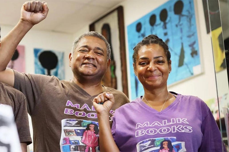 Two local shop owners near USC smile for the camera with their fists up.