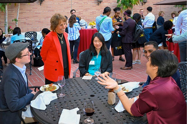 Carol Folt talking to several USC staff members during a luncheon