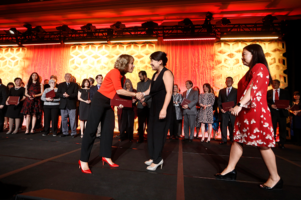 President Folt handing a certificate to a USC staff member during a ceremony