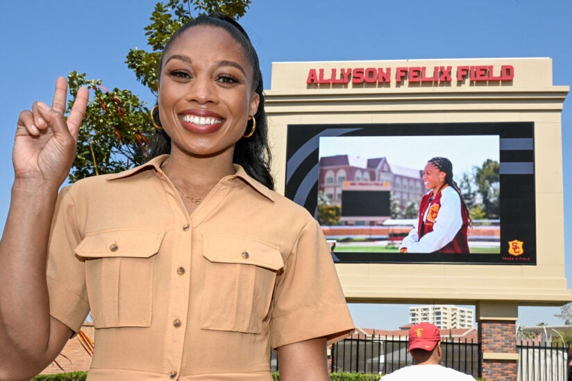 Allyson Felix putting up the trojan sign in front of the Allyson Felix field. 