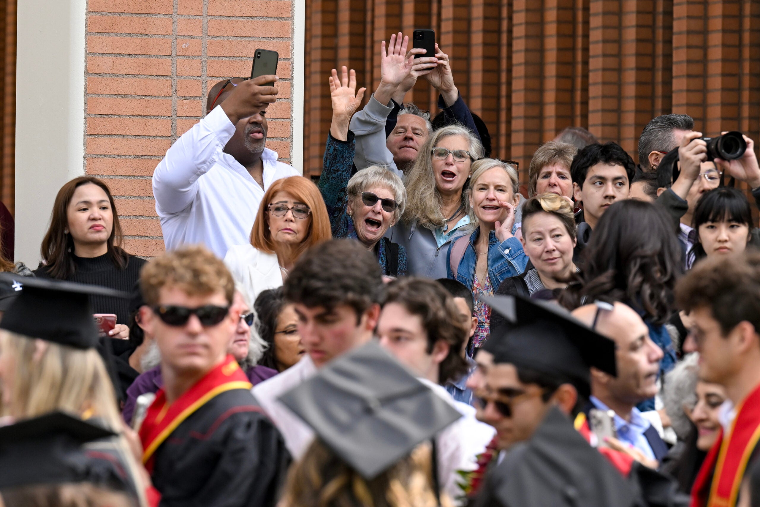 Family and friends yell to the graduates during the opening procession at the start of the 140th commencement ceremony at the University of Southern California, May 12, 2023. (Photo/Gus Ruelas)