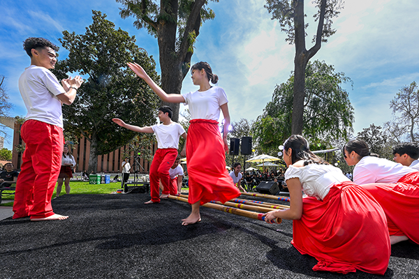 During Asian American and Pacific Islander Heritage Month, performers wearing traditional outfits of red bottoms and white tops while dancing at an opening event on campus at USC.