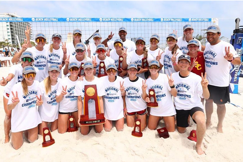 The girls beach volleyball team posing in front of the court.