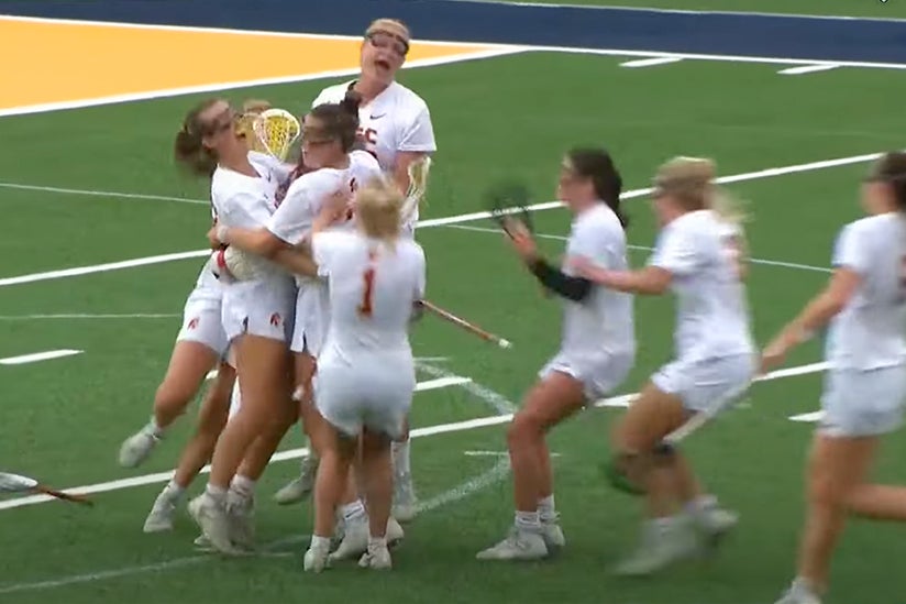 The woman's lacrosse team celebrating on a field. 